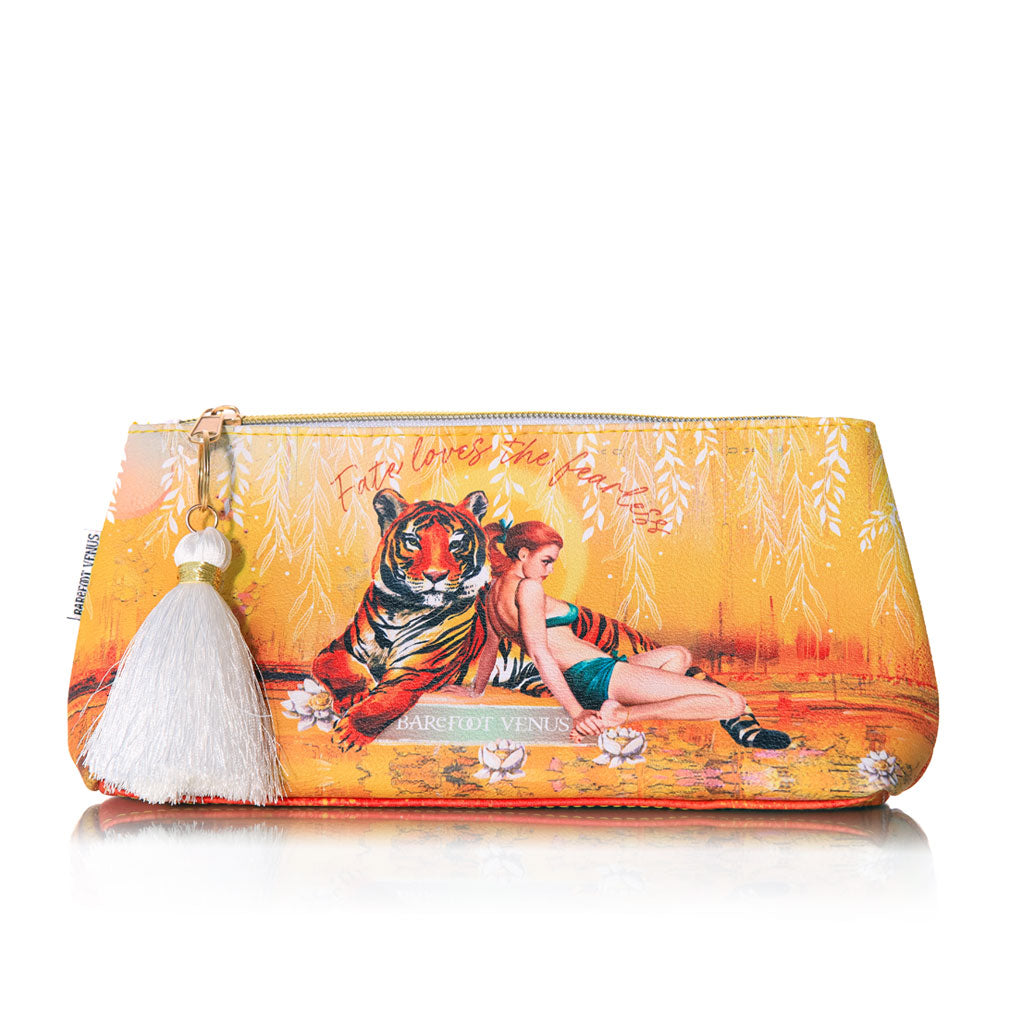 A yellow/orange pouch with a tiger and woman design featuring a white tassel, held by a person wearing a yellow dress.