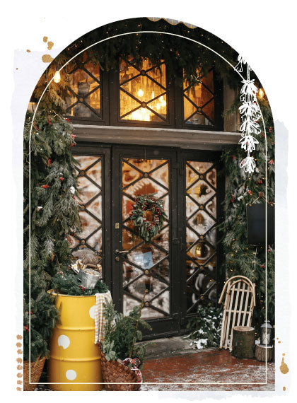 Winter scene of door covered in snow with a wreath and tree branches.
