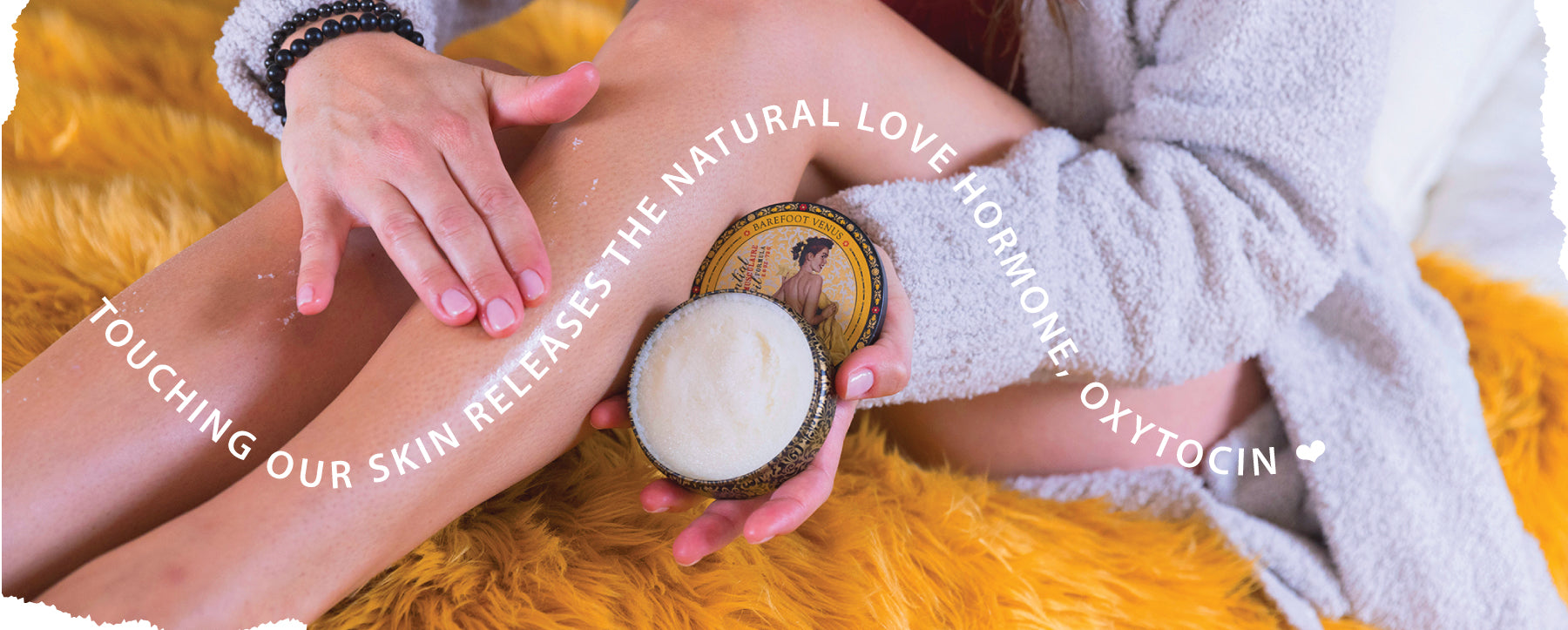 Banner of a woman applying Barefoot Venus Muscle Rub to her legs. Text in a wave across the image reads "Touching our skin releases the natural love hormone, oxytocin".