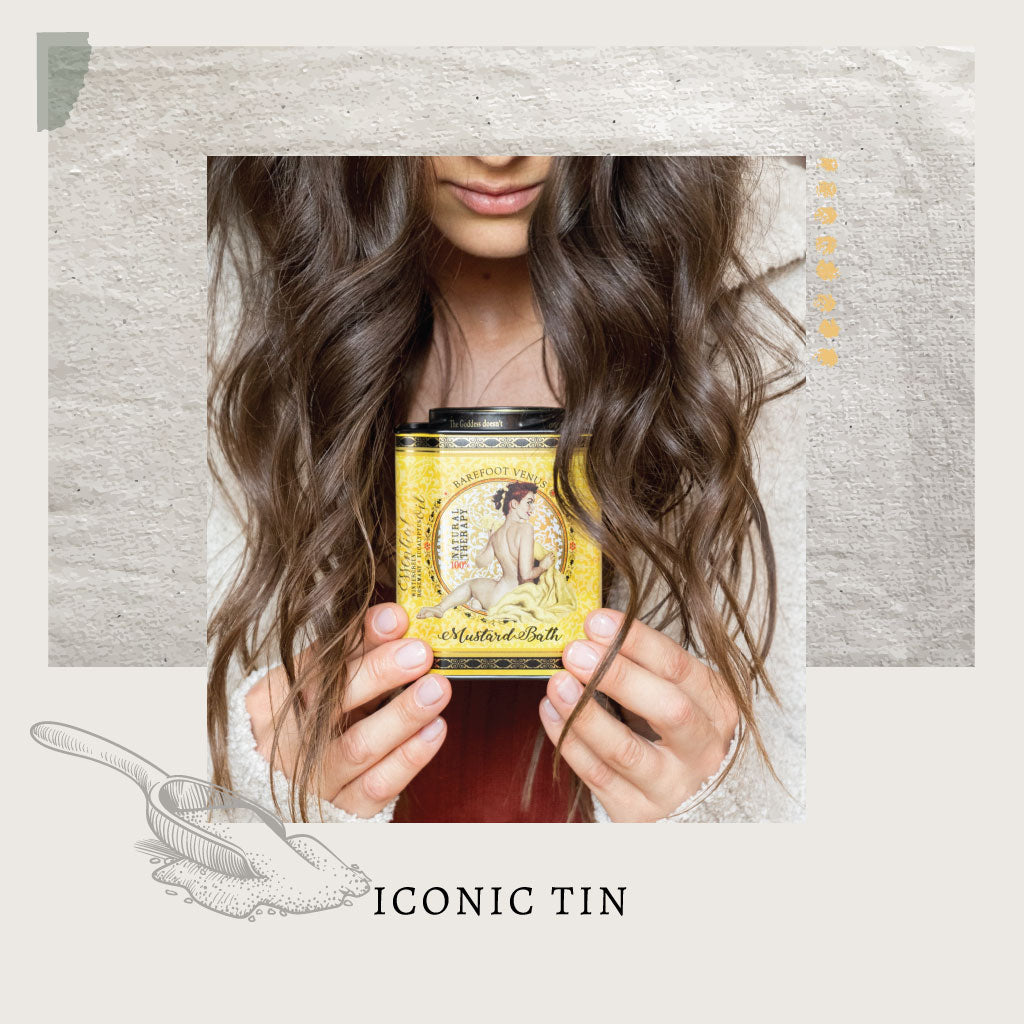 Woman with brown hair holding a tin of Barefoot Venus Mustard Bath Soak  in her hands with a decorative frame and text that reads 'Iconic Tin'.