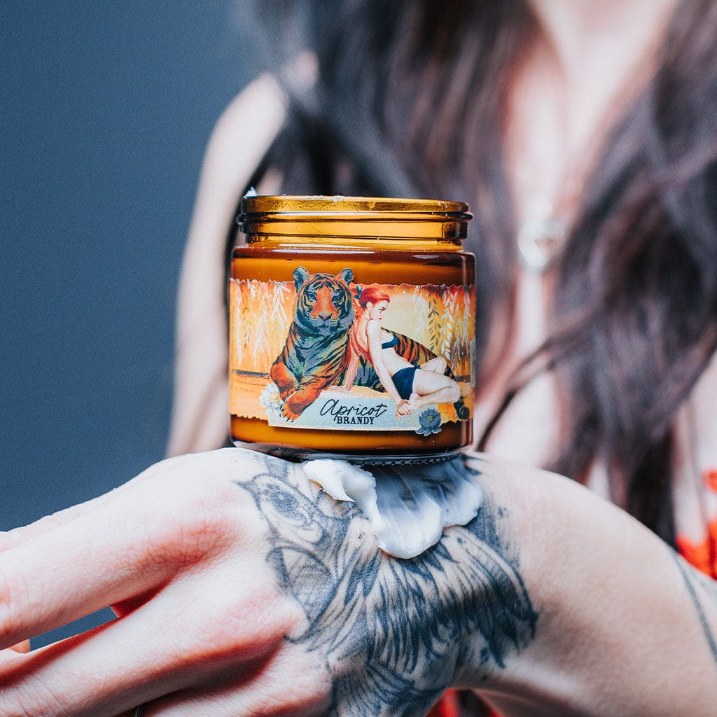 A person holding a jar of Apricot Brandy instant hand repair with a label featuring illustrations of a tiger and woman.